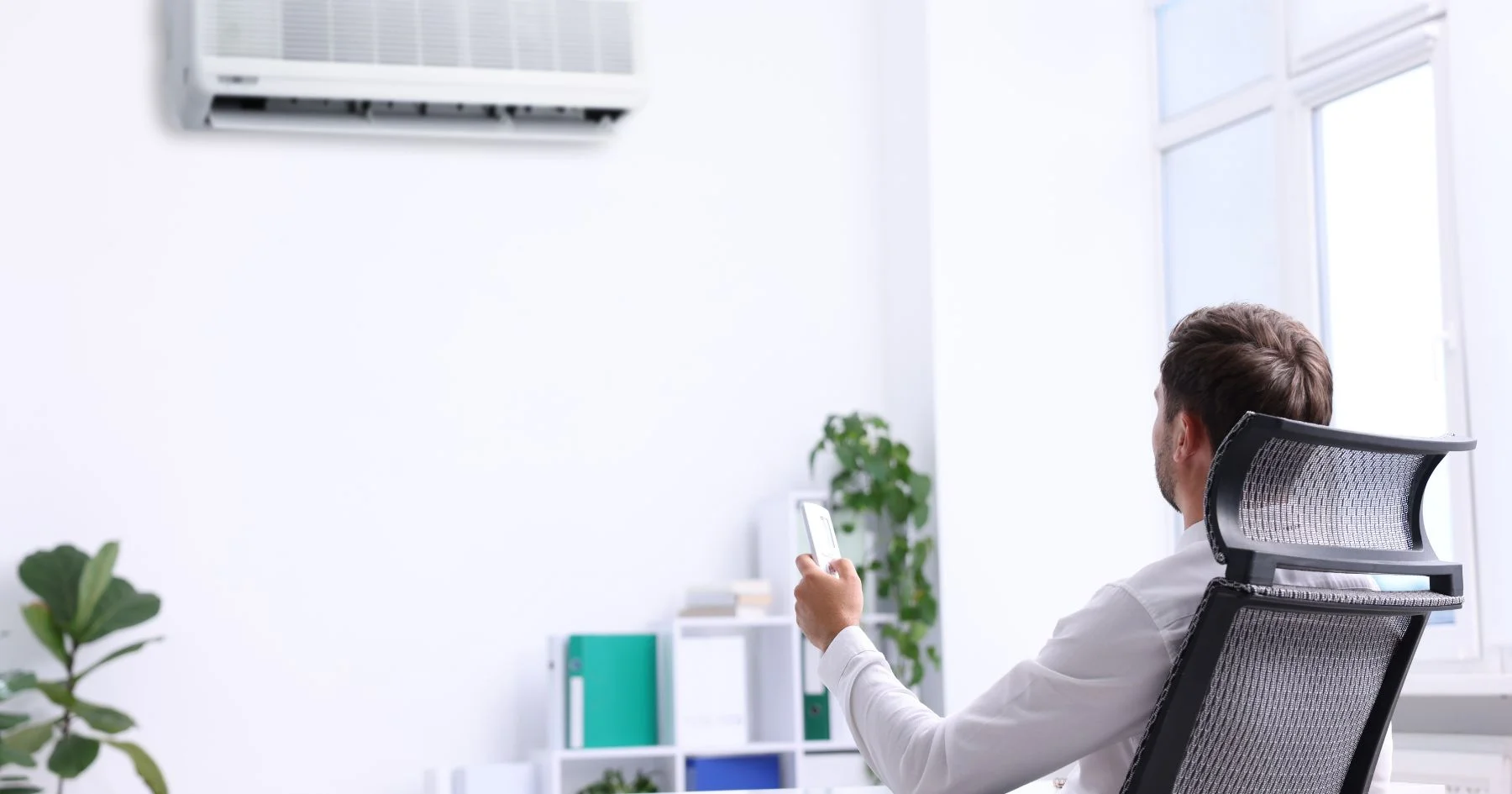 Man using remote control for wall-mounted air conditioner