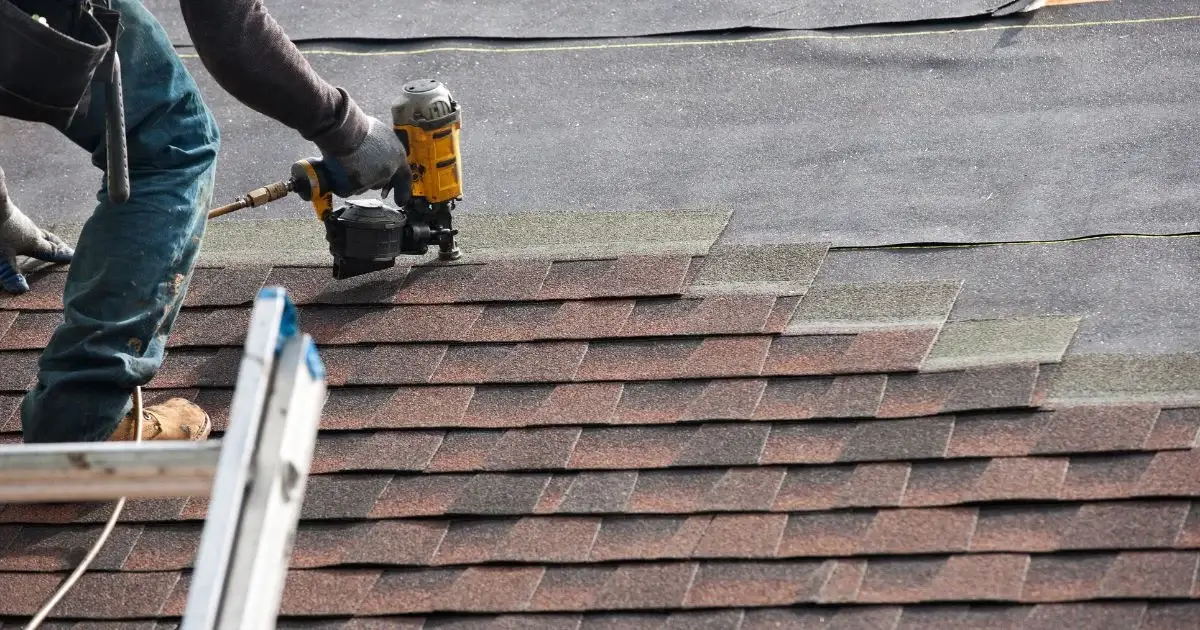 Contractor installing asphalt shingles on residential roof