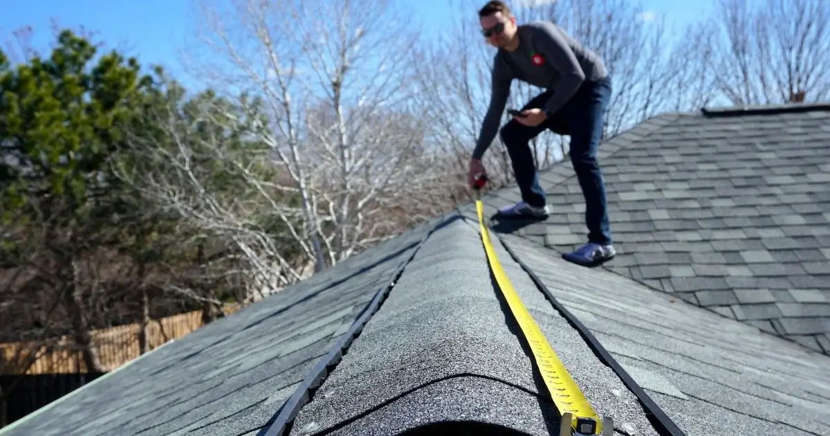 Roofing contractor measuring shingles for roof inspection and estimate